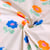 Tissu Jersey Coton Poppy Fleurs bleues et orange fluo sur fond Blanc